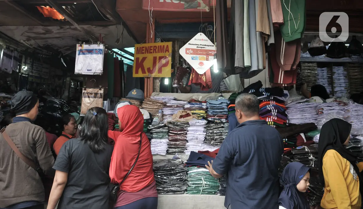 Pembeli memilih seragam sekolah di Pasar Jatinegara, Jakarta, Minggu (5/1/2020). Jelang hari pertama belajar di semester baru, warga terdampak banjir di Kampung Melayu dan sekitarnya terpaksa membeli seragam baru untuk anaknya akibat banjir yang merendam rumah mereka. (merdeka.com/Iqbal Nugroho)