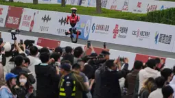 Untuk pertama kalinya, robot humanoid berkompetisi secara resmi berdampingan dengan ribuan pelari manusia dalam lintasan sejauh 21,0975 km. Tampak dalam foto, para jurnalis merekam saat sebuah robot berkompetisi dalam Beijing E-Town Half Marathon dan Humanoid Robot Half-Marathon yang diadakan di pinggiran Beijing, Minggu 19 April 2026. (AP Photo/Andy Wong)