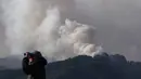 Kebakaran hutan yang terjadi sejak Rabu 22 April 2026, menghanguskan lebih dari 1.100 hektar lahan dan memaksa ribuan warga mengungsi. Tampak dalam foto, seorang pria menggunakan teropong untuk melihat berbagai bagian kebakaran yang terjadi di sekitar kota Otsuchi, Prefektur Iwate, Jepang pada Sabtu 25 April 2026. (ANDREW CABALLERO-REYNOLDS/AFP)