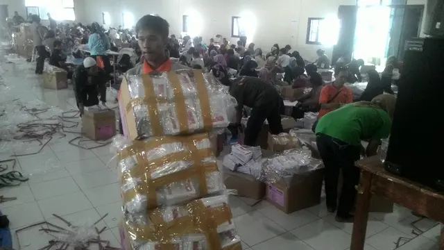 Satu petugas tengah memindahkan tumpukan surat suara, sementara ratusan lainnya sibuk melakukan pelipatan