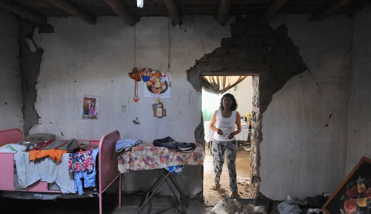 Seorang wanita mengamati rumahnya yang rusak setelah gempa di Acari, Peru, (14/1). Dua orang tewas akibat kejadian gempa berkekuatan 7,1 skala Richter ini. (AP Photo / Charlie Reyna)