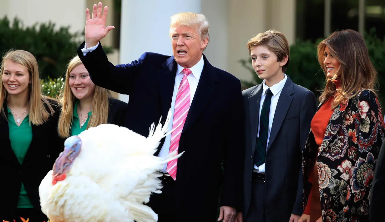Presiden AS, Donald Trump bersama Ibu Negara Melania Trump dan putra Barron berpartisipasi dalam upacara pengampunan kalkun di Hari Thanksgiving yang ke 70 tahun di Taman Mawar Gedung Putih di Washington, AS, (21/11). (AP Photo / Manuel Balce Ceneta)