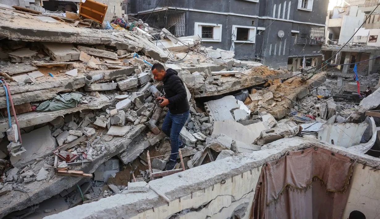 Para pria melihat reruntuhan rumah yang hancur akibat serangan Israel di Khan Younis, Jalur Gaza selatan, pada Rabu 29 Oktober 2025. Diketahui pula, Israel menggempur Khan Younis, Gaza Tengah, dan bahkan di perkemahan pengungsi Bureij. (BASHAR TALEB/AFP)