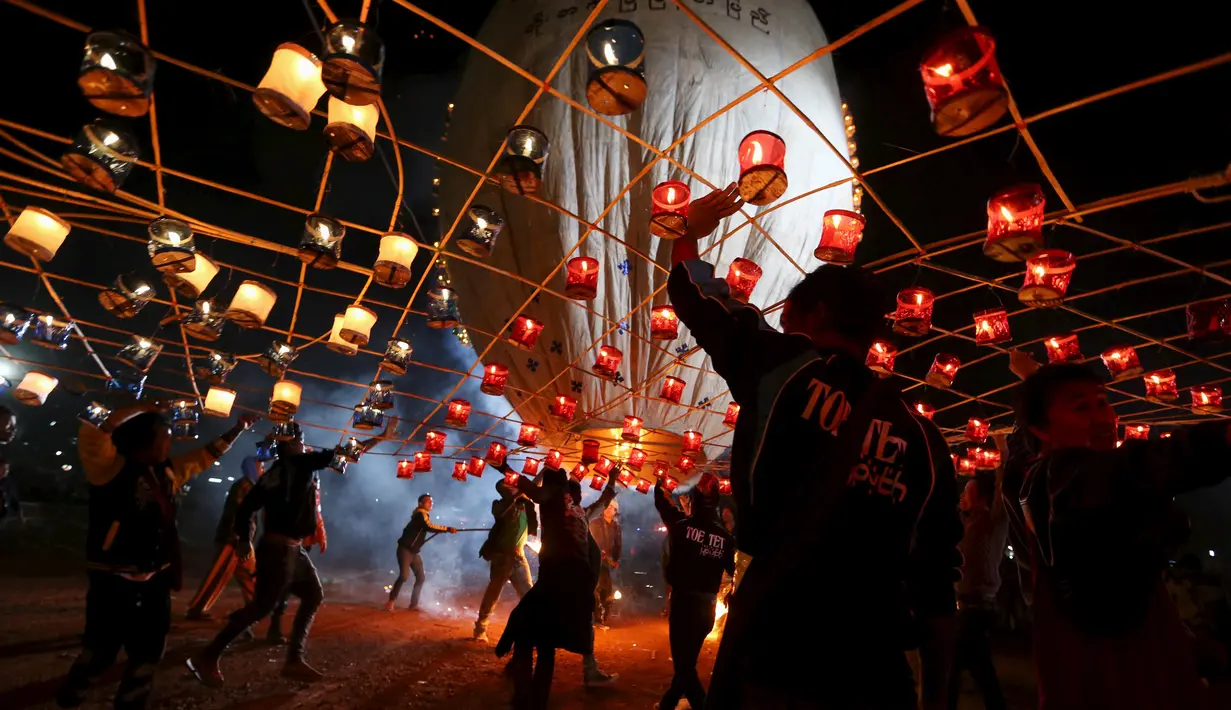 Warga menyalakan Lampion buatan tradisional sebelum melepaskannya ke langit selama festival tahunan Tazaungdaing di Taunggyi, Myanmar (19/11). (REUTERS/Soe Zeya Tun)