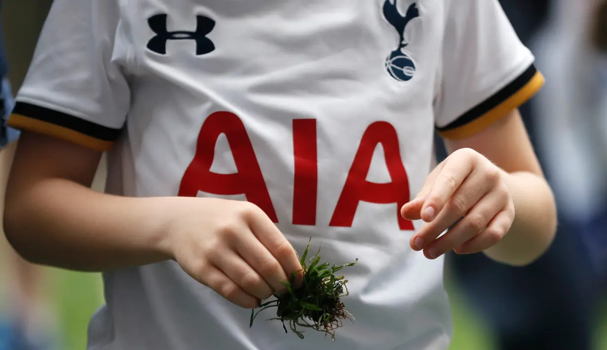 Seorang supporter Tottenham Hotspur membawa rumput yang diambilnya usai pertandigan di Liga Inggris di stadion White Hart Lane, London, (14/5). The Lilywhites akan bermarkas di Stadion Wembley sembari menunggu stadion baru jadi. (AP/Frank Augstein)