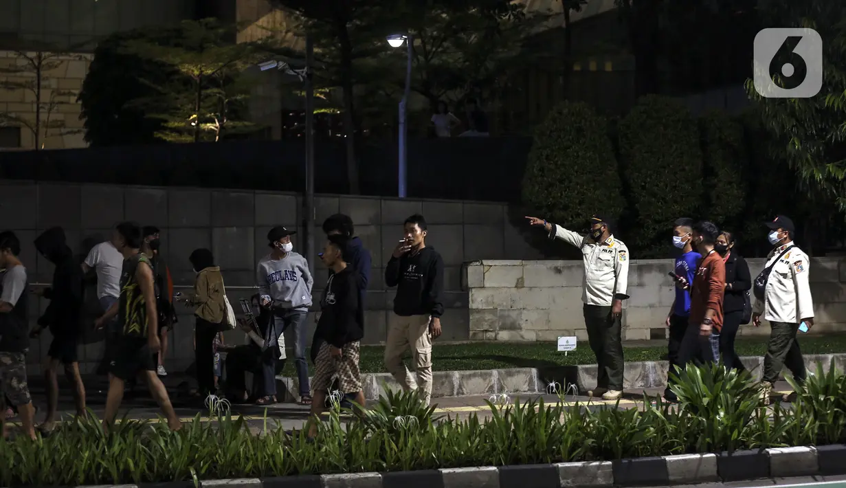 Satpol PP membubarkan kerumunan warga saat perayaan malam Tahun Baru di Jakarta, Jumat (31/12/2021). Polda Metro Jaya melakukan pengendalian mobilitas Crowd Free Night (malam bebas keramaian) dengan membubarkan warga yang nekat keluar rumah dan tidak mematuhi aturan. (Liputan6.com/Johan Tallo)