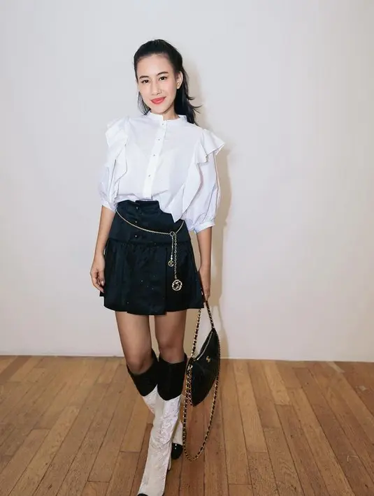 Tak hanya mengenakan brand lokal, di acara kasual, Shenina pun mengenakan outfit serba Chanel. Dari atasan putih ruffle lengan balon dipadukan mini skirt pleated hitam dan mengenakan belt rantainya. Ia pun membawa tas Chanel hitam dan mengenakan boots putih. [@sheninacinnamon]
