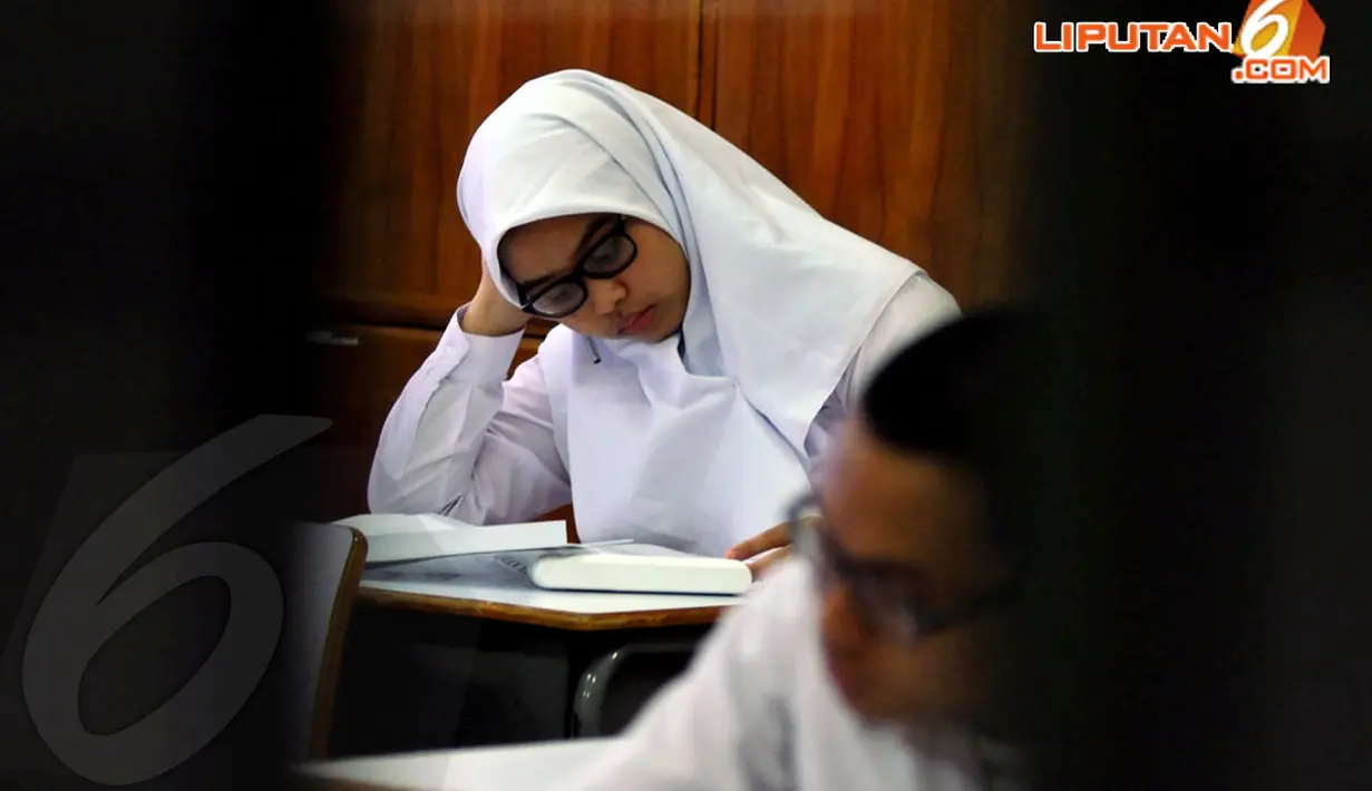 Salah satu siswi SMA 65 Jakarta, terlihat begitu serius membaca soal- soal ujian nasional hari pertama pada Senin 14 April 2014. (Liputan6.com/JohanTallo)