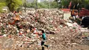 Warga melintas di dekat tumpukan sampah yang ada di Tempat Pembuangan Sampah Sementara Kalibata, Jakarta, Rabu (4/11/2015). Penumpukan sampah terkait aksi pemblokadean jalan menuju TPST Bantar Gebang. (Liputan6.com/Helmi Fithriansyah)