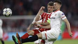 Pemain Bayern, Thomas Mueller (kiri) berebut bola dengan pemain Sevilla, Clement Lenglet pada leg kedua perempat final Liga Champions di Allianz Arena stadium, Munich, (11/4/2018). Bayern lolos ke semifinal dengan agregat 2-1. (AP/Matthias Schrader)