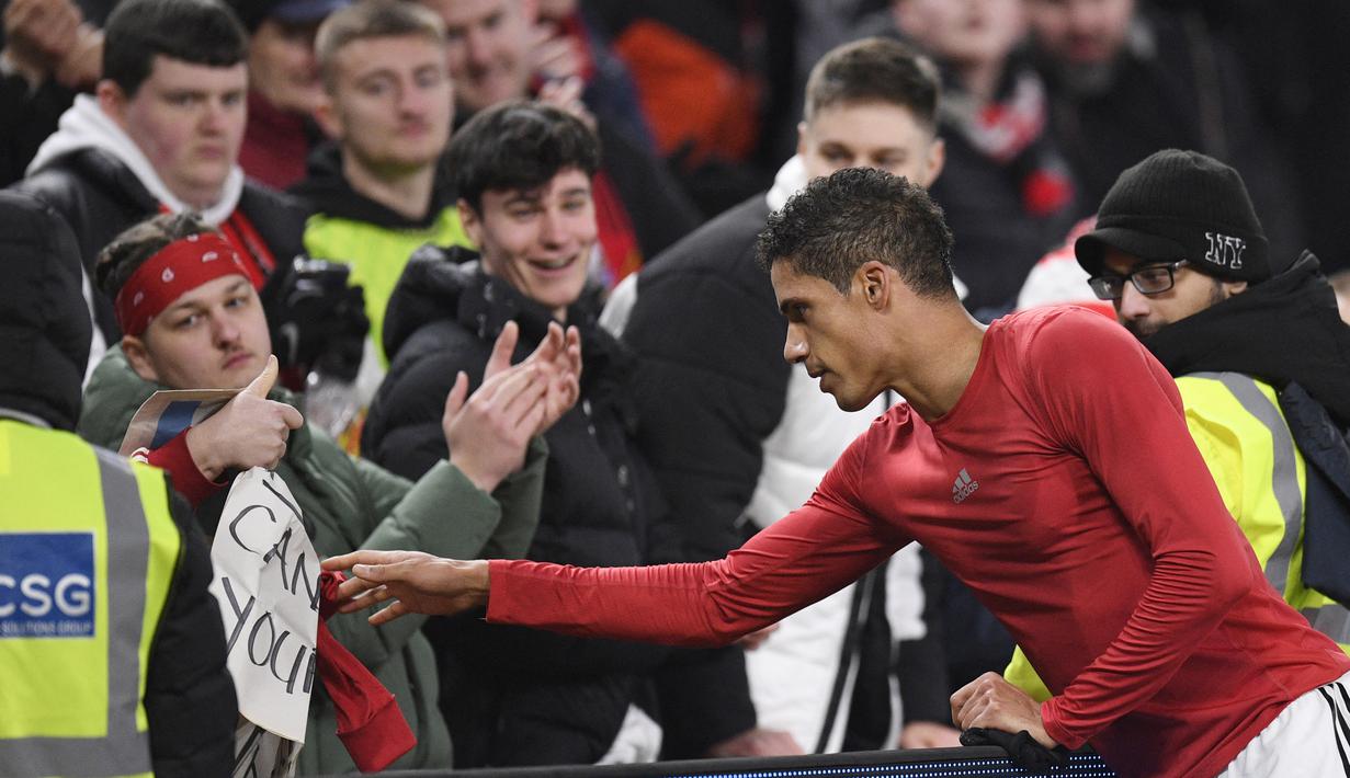 Pemain Manchester United, Raphael Varane, memberikan jersey kepada fans setelah laga Leeds United pada laga Liga Inggris di Stadion Old Trafford, Rabu (8/2/2023). Hasil imbang ini membuat MU tertahan di peringkat ke-3 dengan 43 poin, gagal menyamai poin Man City yang ada satu strip di atas dengan 45 poin. Bagi Leeds, hasil ini cukup untuk mengangkat mereka ke posisi 16 dengan 19 poin. (AFP/Oli Scarff)