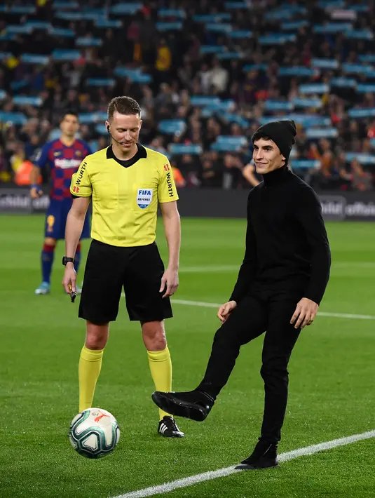 Pembalap Repsol Honda, Marc Marquez menendang bola sebelum pertandingan Liga Spanyol "El Clasico" antara Barcelona melawan Real Madrid di Camp Nou Stadium (18/12/2019). (AFP/Lluis Gene)