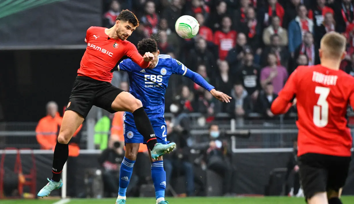 Pemain depan Rennes Martin Terrier berebut bola dengan bek Leicester City James Justin (tengah) pada leg kedua babak 16 besar Europa Conference League di Roazhon Park, Jumat (18/3/2022) dini hari WIB. Meski kalah dengan skor tipis 1-2, Leicester City tetap lolos ke perempat final. (DAMIEN MEYER/AFP)