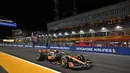 Pembalap tim McLaren, Lando Norris memacu mobilnya saat melintasi tribun dalam balapan F1 GP Singapura 2023 di Marina Bay Street Circuit, Singapura, Minggu (17/9/2023) malam WIB. (AFP/Lillian Suwanrumpha)