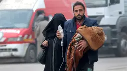 Seorang pria membawa anak dengan infus saat ia melarikan diri lebih dari wilayah yang dikuasai pemberontak di Aleppo, Suriah (12/12). (REUTERS / Abdalrhman Ismail)