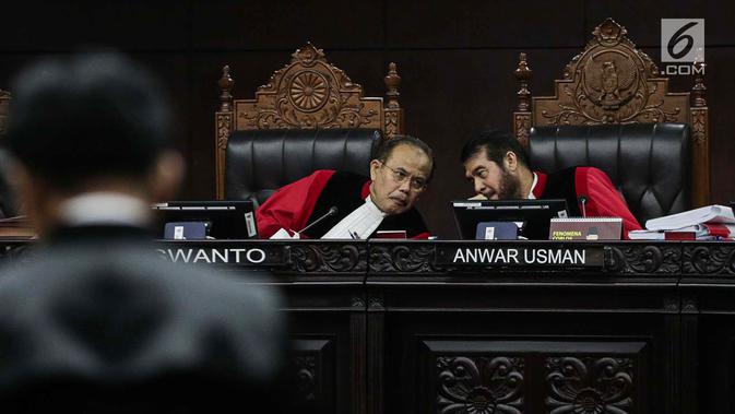 Ketua Majelis Hakim Mahkamah Konstitusi Anwar Usman (kanan) berbincang saat mendengarkan keterangan Ketua Tim Hukum Joko Widodo-Ma'ruf Amin, Yusril Ihza Mahendra dalam sidang sengketa Pilpres 2019 di Gedung MK, Jakarta, Selasa (18/6/2019). (Liputan6.com/Faizal Fanani)