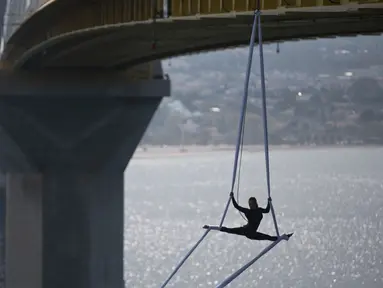 Seorang koreografer dan penari "ekstrem", Katerina Soldatou melakukan tarian di bawah jembatan Rio-Antirio, Yunani selatan, Senin (12/3).  Jembatan ini merupakan jembatan bentang kabel terpanjang di dunia. (AP Photo/Petros Giannakouris)