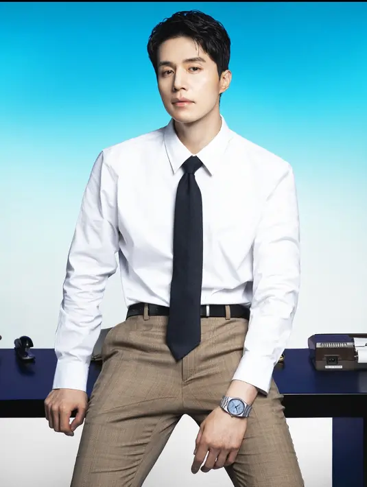 Mengenakan kemeja lengan panjang putih dipadukan dasi hitam dan celana hitam, Lee Dong Wook melengkapi tampilannya dengan jam tangan tangan strap stainless warna dial biru.  [dok. Tissot]