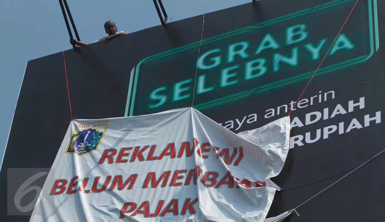 Petugas memasang spanduk bertuliskan "Reklame Ini Belum Bayar Pajak" di Kawasan Kebayoran Lama, Jakarta, Kamis (23/2). Razia oleh Satpol PP dan Dinas BP2T tersebut menertibkan reklame yang tidak membayar pajak. (Liputan6.com/Gempur M Surya)