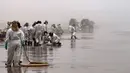 Petugas kebersihan bekerja untuk mengeluarkan minyak dari Pantai Cavero di Callao, Peru, 26 Januari 2022. Pembersihan Pantai Cavero dari tumpahan minyak kapal tanker Mare Doricum yang dihantam gelombang akibat letusan gunung berapi Tonga masih terus dilakukan. (Cris BOURONCLE/AFP)