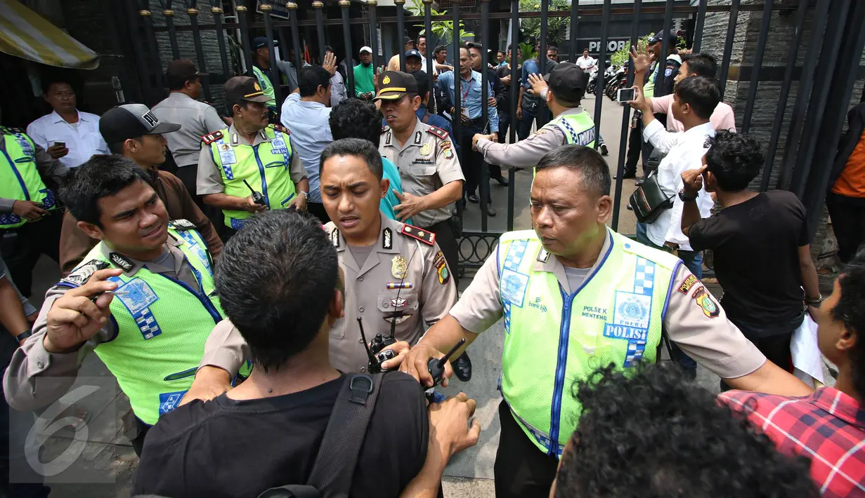 Polisi mencoba menahan massa dari Massa dari Solidaritas Pergerakan Mahasiswa Indonesia yang memaksa melakukan demo di depan Kantor DPP Partai NasDem, Jakarta, Senin (18/1). Kejadian tersebut juga diwarnai aksi lempar batu.(Liputan6.com/Immanuel Antonius)