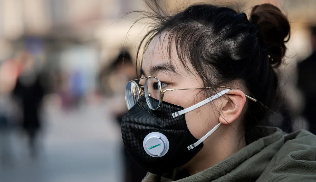 Seorang perempuan mengenakan masker penutup mulut berjalan menuju  stasiun kereta api Beijing untuk mudik Tahun Baru Imlek pada Selasa (21/1/2020). Wabah virus korona seperti SARS yang menyebar di China dan mencapai tiga negara Asia lainnya bisa menular dari manusia ke manusia. (NICOLAS ASFOURI/AFP)