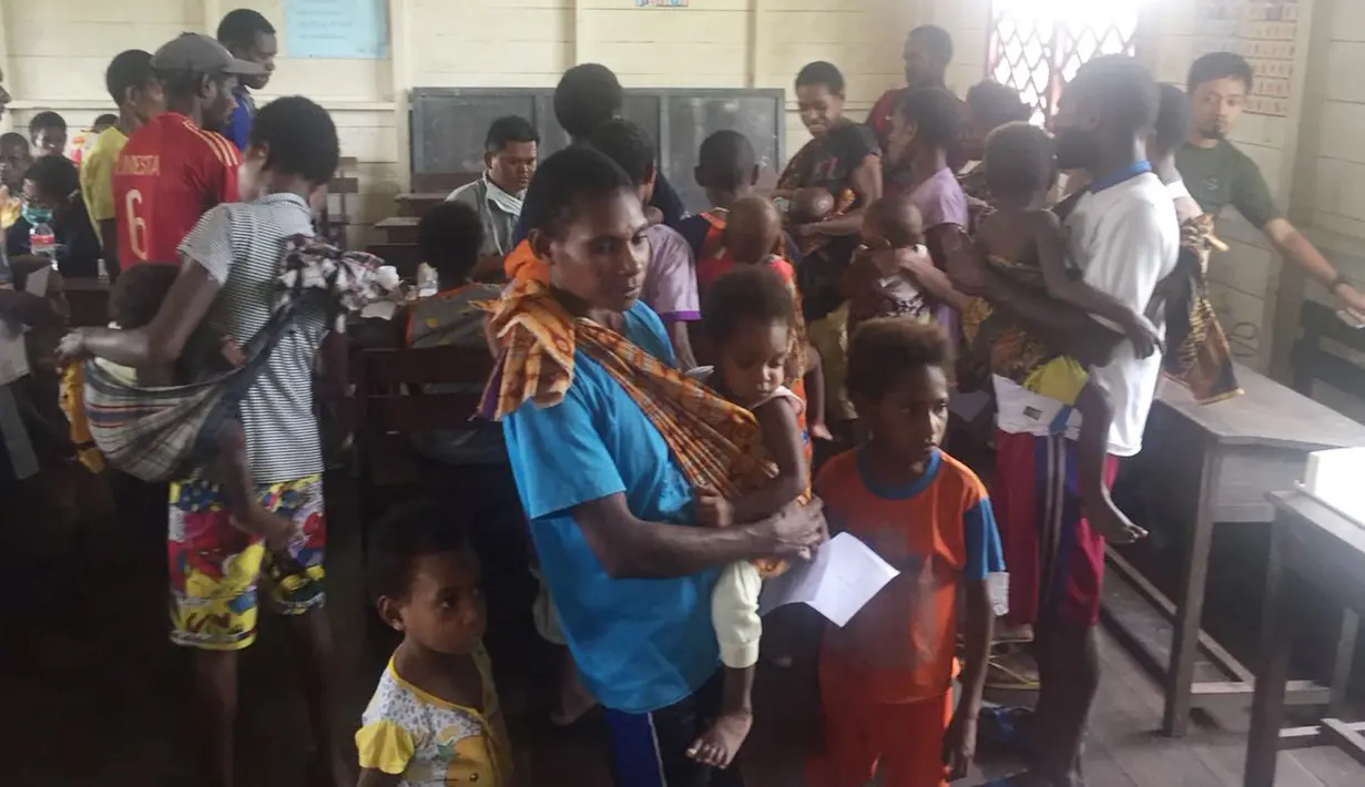 Sejumlah warga dan anak mereka antre mendapatkan pengobatan dan vaksin campak di Kabupaten Asmat, Papua, Jumat (19/1). Satgas Kesehatan TNI menyalurkan bantuan berupa vaksin ke kampung-kampung terpencil di Kabupaten Asmat. (LIputan6.com/Pool/Puspen TNI)