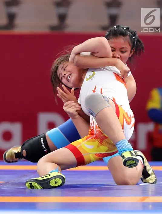 Pegulat Indonesia, Ayuningtias Mutiara (belakang) mengunci pegulat Uzbekistan, Esenbaeva Nabira pada babak perdelapan final 57 kg putri dalam Asian Games 2018 di JCC Senayan, Senin (20/8). Ayuningtias kalah dengan skor 0-7. (Liputan6.com/Fery Pradolo)