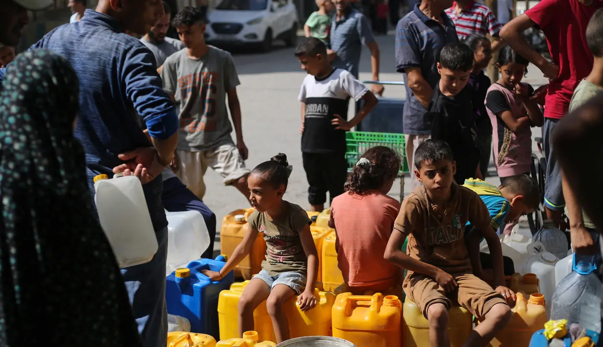 Antrean panjang terlihat di sejumlah titik distribusi air, tak hanya orang dewasa, anak-anak pun terpaksa ikut menunggu giliran untuk mendapatkan pasokan. (Eyad BABA/AFP)