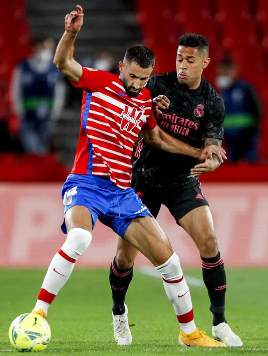Pemain Granada Maxime Gonalons (kiri) berebut bola dengan pemain Real Madrid Casemiro pada pertandingan La Liga di Stadion Los Carmenes, Granada, Spanyol, Kamis (13/5/2021). Real Madrid menang telak 4-1 atas Granada. (AP Photo/Fermin Rodriguez)