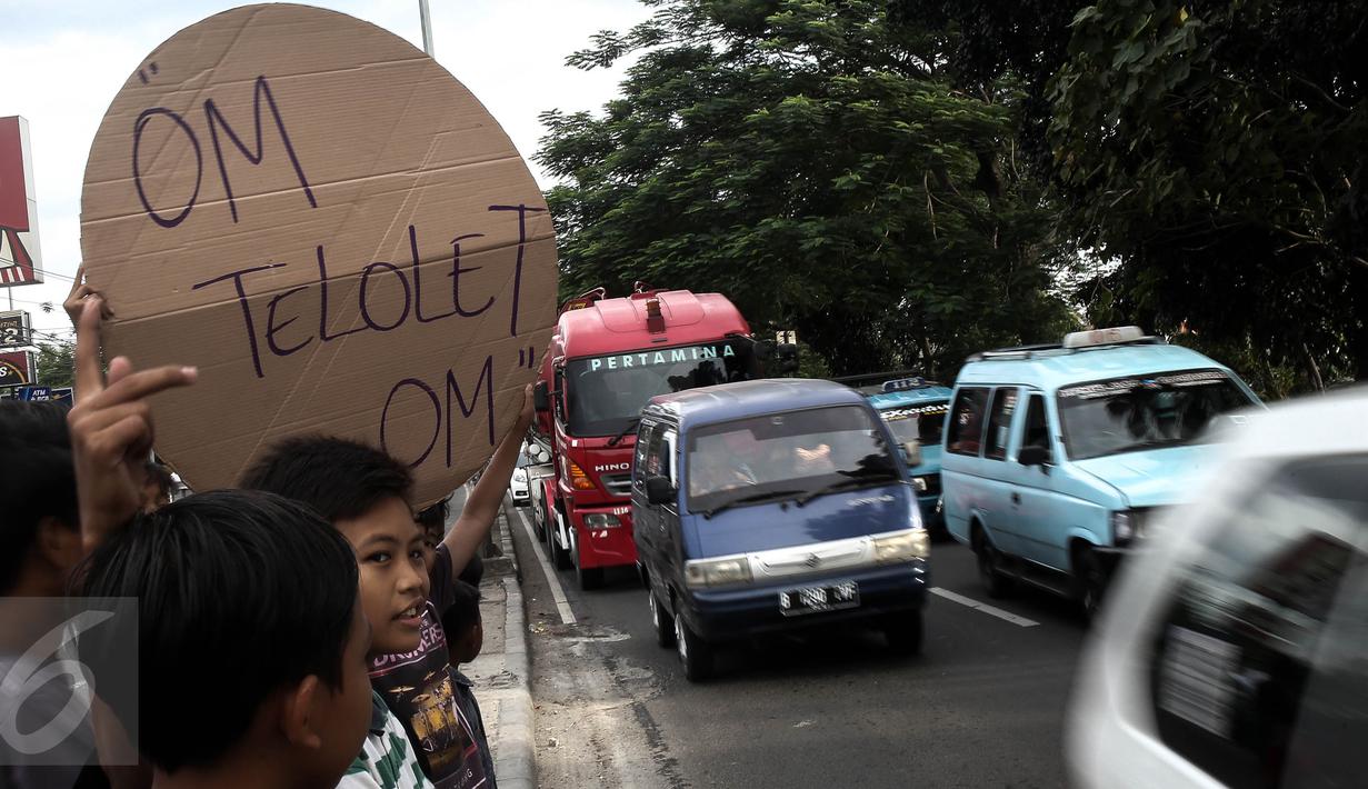 Anak-anak  saat meminta bunyi klakson telolet ke bus yang lewat di Jalan Raya Bogor, Jakarta, Sabtu (24/12). Fenomena ini mendunia setelah beberapa artis dan tokoh terkenal dunia berkomentar di media sosial. (Liputan6.com/ Faizal Fanani)