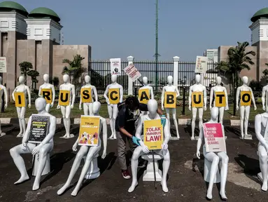 Aktivis Greenpeace Indonesia menata puluhan maneken saat menggelar aksi damai di depan gerbang kompleks DPR, Jakarta Pusat, Senin (29/6/2020). Aksi tersebut dilakukan sebagai bentuk penolakan terhadap RUU Omnibus Law. (Liputan6.com/Johan Tallo)
