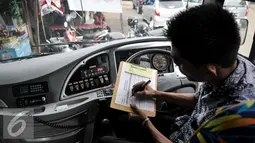 Petugas bus Transjakarta melakukan pengecekan jadwal keluar masuk bus di Terminal Depok, Jumat (22/7). Perubahan rute tersebut bertujuan agar bus bisa mengangkut penumpang di sekitar Bumi Perkemahan Cibubur. (Liputan6.com/Yoppy Renato)