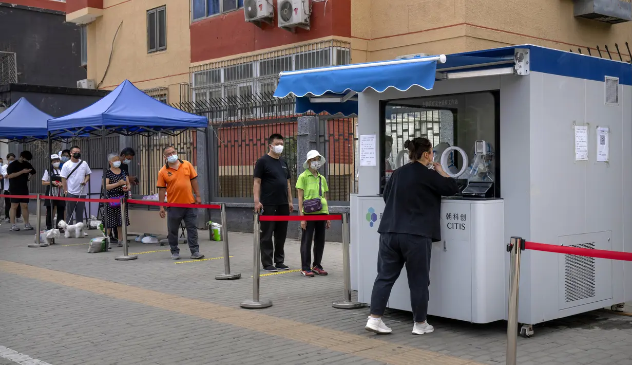 Orang-orang yang mengenakan masker mengantre untuk tes virus corona COVID-19 di tempat pengujian pada hari ketiga tes massal untuk jutaan penduduk di Distrik Chaoyang, Beijing, China, 15 Juni 2022. (AP Photo/Mark Schiefelbein)