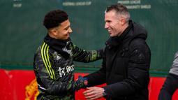 Pemain Manchester United, Jadon Sancho (kiri) bersalaman dengan Robin Van Persie yang merupakan mantan pemain MU saat akan menjalani sesi latihan di Carrington, Rabu (22/2/2023). (Twitter/Manchester United)
