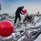 Ogun Sever Okur, pria Turki berusia 38 tahun menggantung balon di atas puing-puing bangunan yang runtuh di Antakya, Turki selatan pada 21 Februari 2023, menyusul gempa berkekuatan 6,4 yang melanda pada 20 Februari, dua minggu setelah gempa berkekuatan 7,8 gempa berkekuatan besar melanda dekat Gaziantep dan telah menewaskan lebih dari 44.000 orang. (AFP/Sameer Al-Doumy)