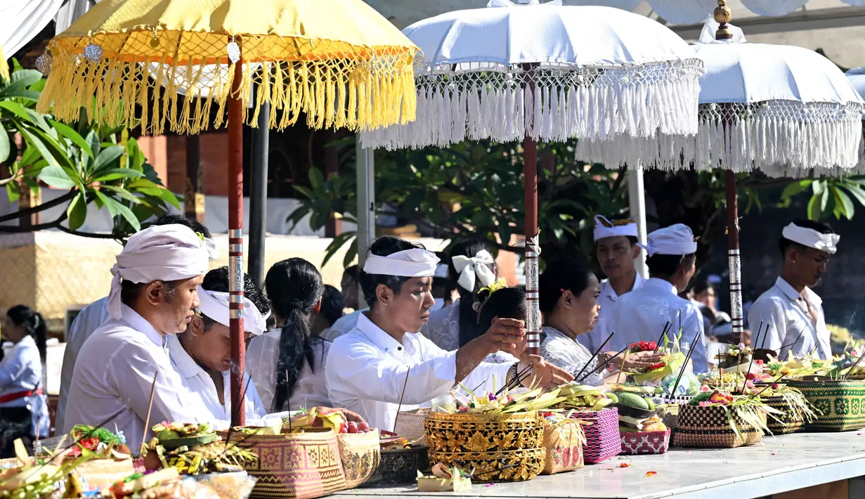 Umat Hindu meletakkan sesajinya di atas meja untuk merayakan Hari Raya Galungan di sebuah pura, Denpasar, Bali, Rabu 17 Juni 2026. (SONNY TUMBELAKA/AFP)