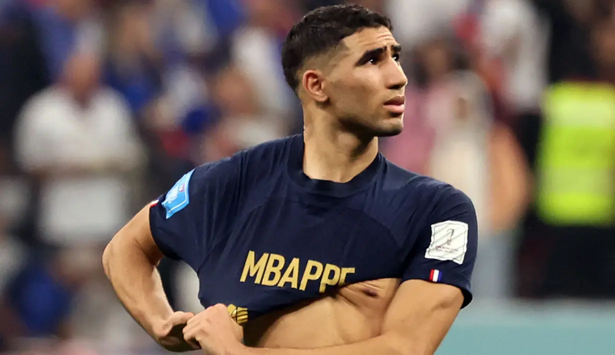 Pemain Maroko, Achraf Hakimi mengenakan baju milik pemain Prancis, Kylian Mbappe berjalan meninggalkan lapangan setelah laga semifinal Piala Dunia 2022 yang berlangsung di Al Bayt Stadium, Qatar, Rabu (14/12/2022) waktu setempat. Prancis menang dengan skor 2-0 melalui gol Theo Hernandez dan Randal Kolo Muani. (AFP/Karim Jaafar)