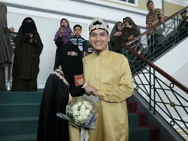 Pesinetron Egi John bersama pasangannya Kamilia Yasmin menunjukan buku nikah usai akad nikah di kawasan Cinere, Jakarta, Sabtu (1/7). (Liputan6.com/Herman Zakharia)