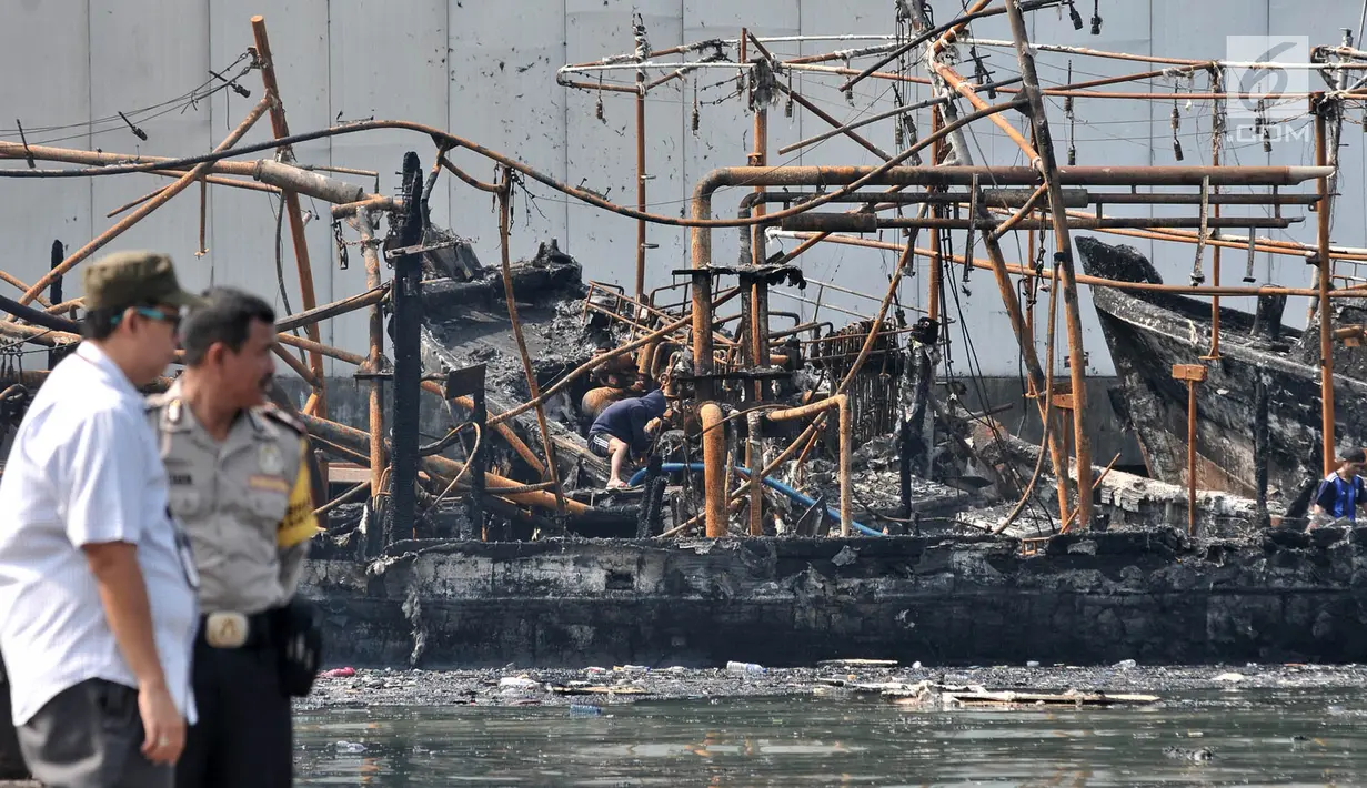 Polisi memantau proses pendinginan kapal yang ludes dilalap api di Pelabuhan Muara Baru, Jakarta, Minggu (24/2). Saat ini belum ada penetapan tersangka karena sejumlah saksi masih diperiksa. (Merdeka.com/Iqbal Nugroho)