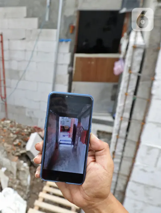 Salah satu kerabat pemilik rumah menunjukkan foto rumahnya yang terhimpit pembangunan gudang di kawasan Mangga Dua Dalam, Jakarta, Kamis (12/12/2019). (Liputan6.com/Herman Zakharia)