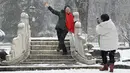 Seorang wanita berpose saat salju turun di sebuah taman di Beijing (16/12/2019). Badai salju dapat membawa kesenangan dan juga masalah bagi penduduk Beijing.  (AFP Photo/Wang Zhao)