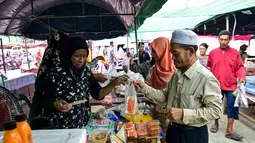 Beragam penganan dan kudapan dijajakan di sejumlah pasar di sekitar jalan-jalan utama kota Narathiwat yang menjadi pusat perburuan menu makanan untuk berbuka puasa bagi warga lokal. Tampak dalam foto, orang-orang membeli makanan untuk berbuka puasa pada hari pertama bulan suci Ramadan 1447 Hijriah di sebuah pasar di provinsi Narathiwat, Thailand selatan, pada Kamis 19 Februari 2026. (Madaree TOHLALA/AFP)