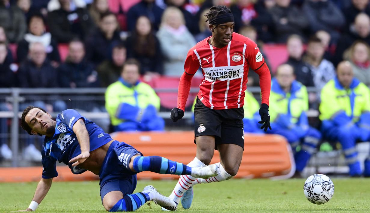 Pemain PSV Eidnhoven, Noni Madueke (kanan) berebut bola dengan pemain Heracles Almelo, Giacomo Quagliata pada laga lanjutan Liga Belanda 2022/2023 di Phillips Stadium, Eindhoven, 6 Maret 2022. Pada bursa transfer Januari 2023, Madueke direkrut Chelsea dengan harga 35 juta euro. (AFP/ANP/Olaf Kraak)
