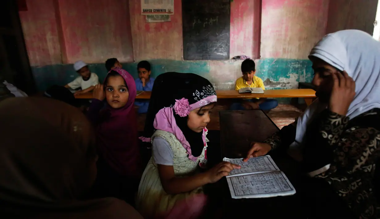 Seorang anak perempuan Kashmir saat membaca Al-Quran di sebuah madrasah lokal selama bulan Ramadan di Srinagar, Kashmir yang dikuasai India, (30/5). Umat muslim di seluruh dunia saat ini tengah menjalani ibadah puasa. (AP Photo / Mukhtar Khan)