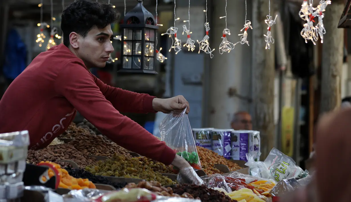 Pedagang Palestina menjual kurma dan rempah-rempah di sebuah pasar menjelang bulan suci Ramadan di Gaza City pada 20 April 2020. Diberlakukannya larangan keluar rumah atau jam malam membuat miliar umat muslim di dunia akan menjalani Ramadan yang berbeda tidak seperti sebelumnya (Xinhua/Yasser Qudih)