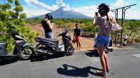 Sejumlah turis mengabadikan pemandangan erupsi Gunung Agung di Kabupaten Karangasem, Bali, Jumat (6/7). Erupsi Gunung Agung mengundang banyak perhatian warga dan wisatawan. (AFP FOTO / Sonny Tumbelaka)