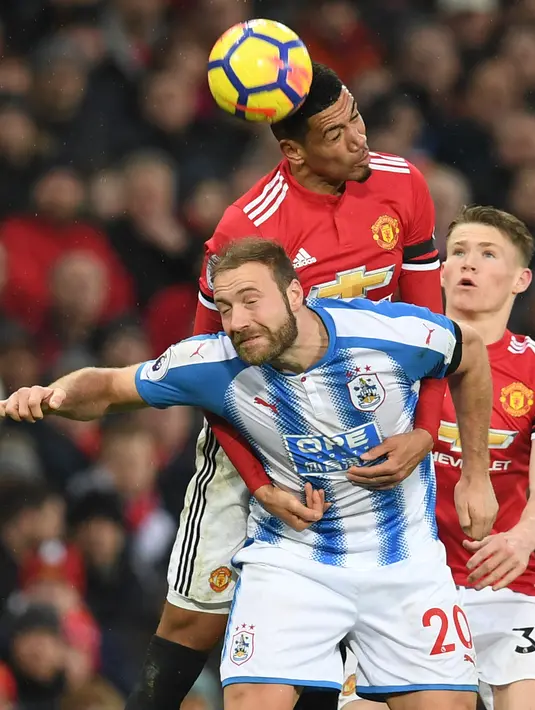 Bek Manchester United Chris Smalling berbut bola di udara dengan striker Hudentfield Town Laurent Depoitre saat pertandingan Liga Inggris di Old Trafford di Manchester (3/2). (AFP Photo/Paul Ellis)
