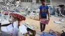 Seorang anak laki-laki menyelamatkan barang-barang dari reruntuhan rumahnya yang hancur akibat serangan Israel di Khan Younis, Jalur Gaza selatan, pada Rabu 29 Oktober 2025. Badan pertahanan sipil Gaza mengatakan pada Rabu 29 Oktober 2025 bahwa puluhan serangan Israel menghantam sejumlah wilayah. (BASHAR TALEB/AFP)