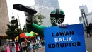 Seperhero membawa poster saat melakukan aksi teaterikal di Bundaran HI, Jakarta, Minggu (16/4). Dalam aksi teaterikal tersebut para superhero menyuarakan untuk terus mendukung KPK. (Liputan6.com/Angga Yuniar)